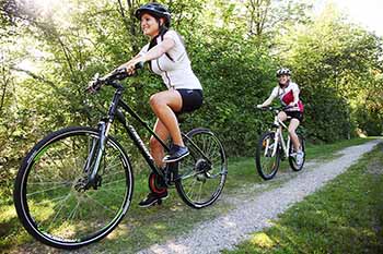 Zwei Frauen im sportlichen Outfit radeln entspannt entlang der Naarn auf einem der beschilderten Rad-KulTOUR-Routen Richtung Donau in der Eben des Machlands im Bezirk Perg